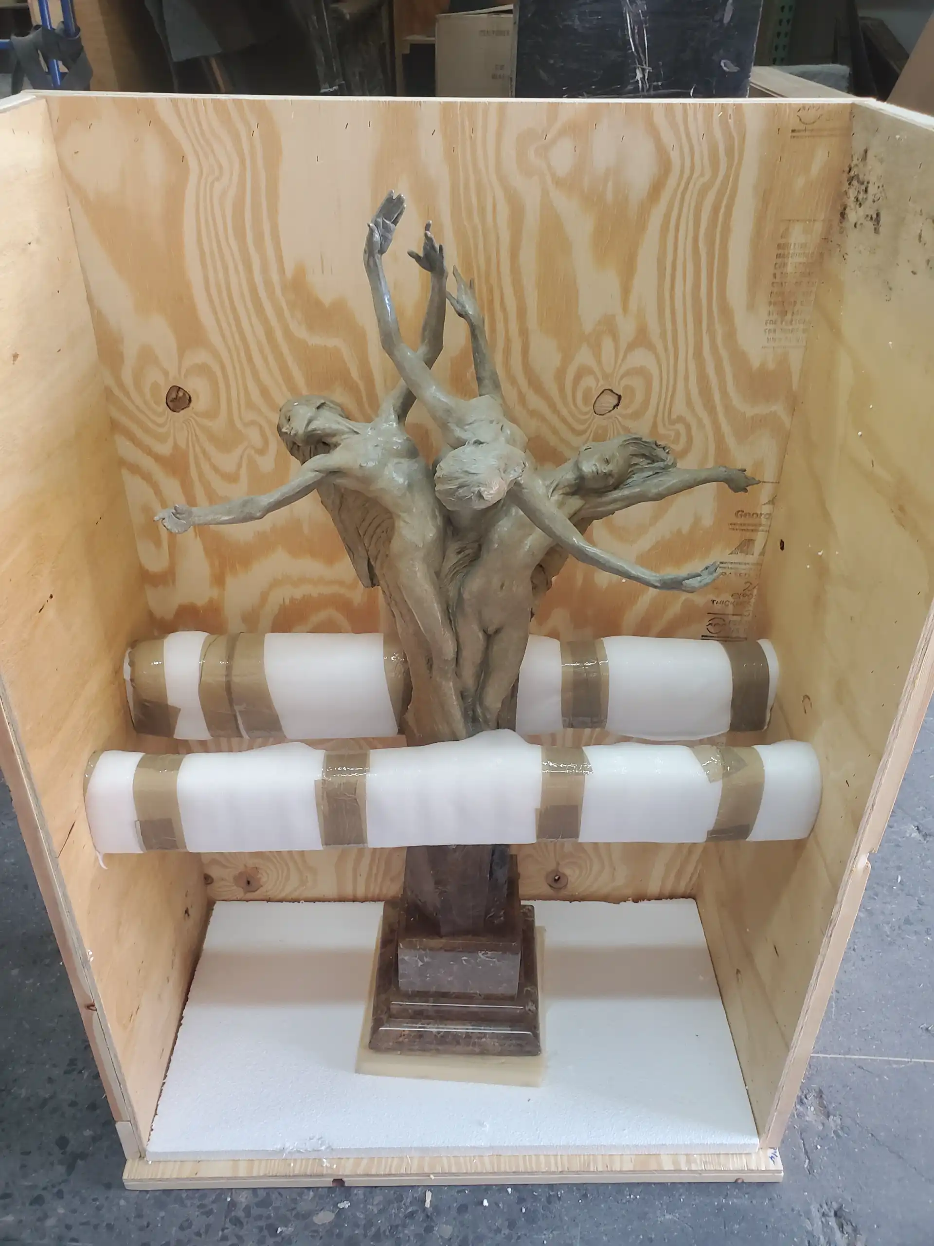 A bronze figural sculpture braced with foam rails inside its crate