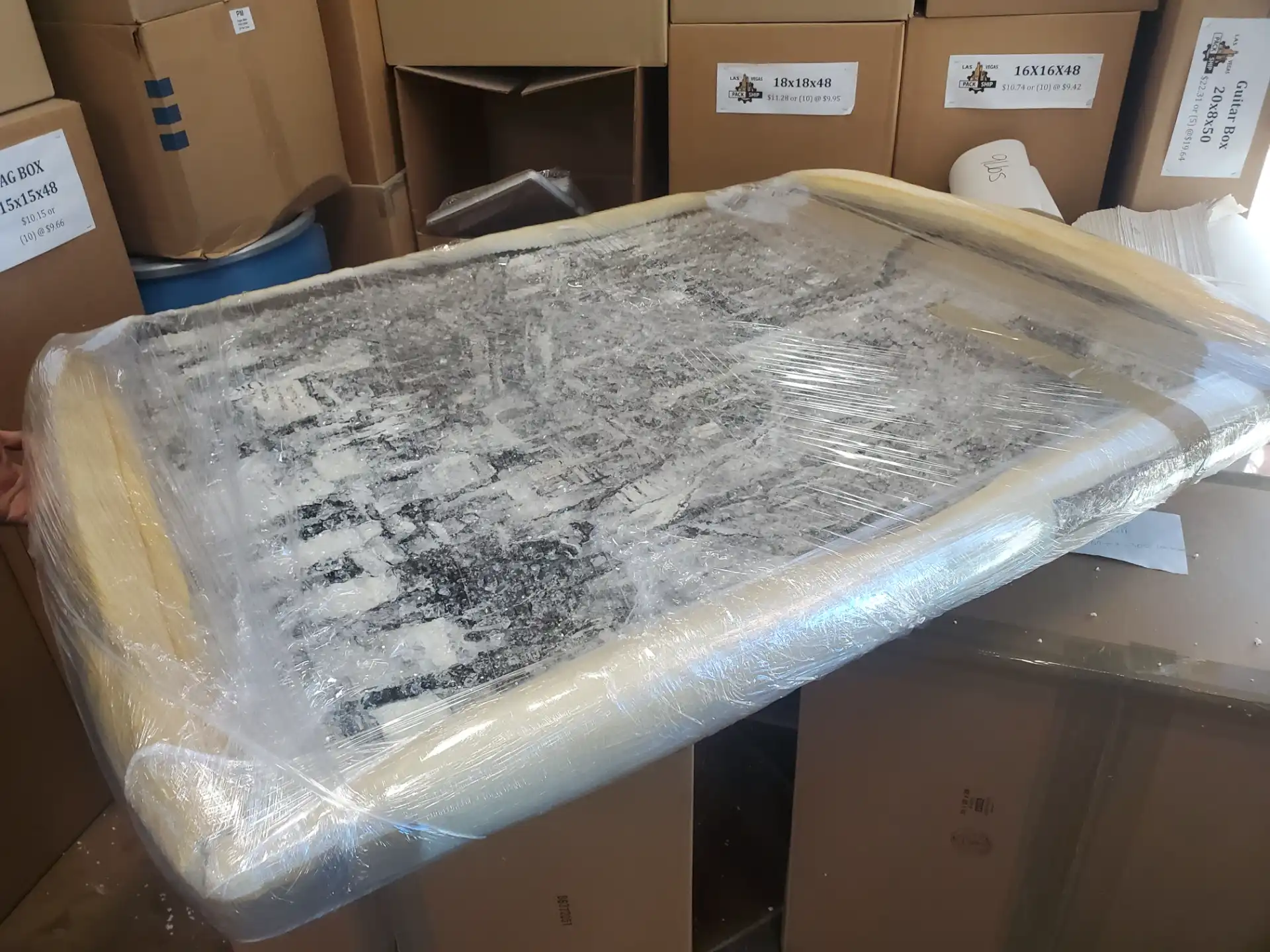 A framed artwork edge-protected with foam and shrink-wrapped for storage