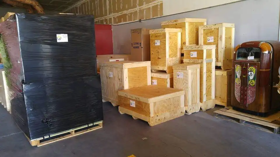 Custom-built wooden crates and a shrink-wrapped jukebox staged on pallets in the warehouse