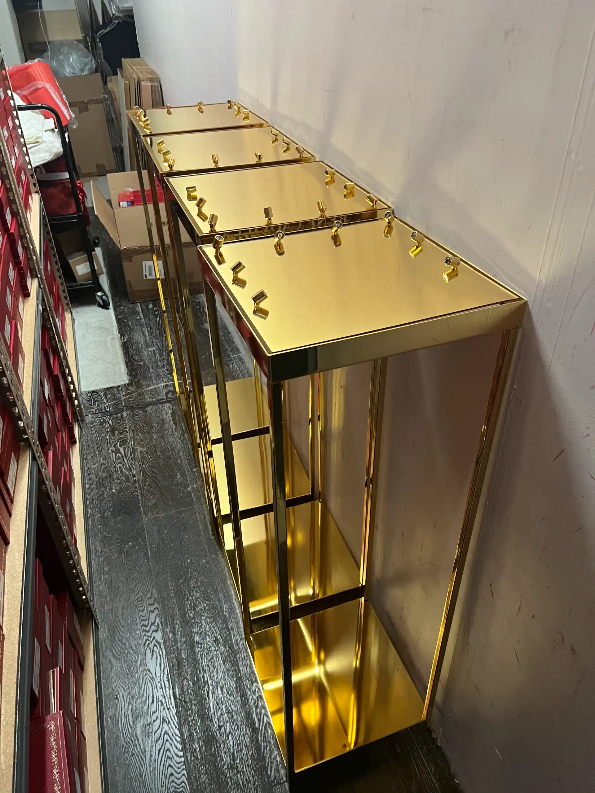 Polished gold retail display fixtures stored upright alongside shelved inventory